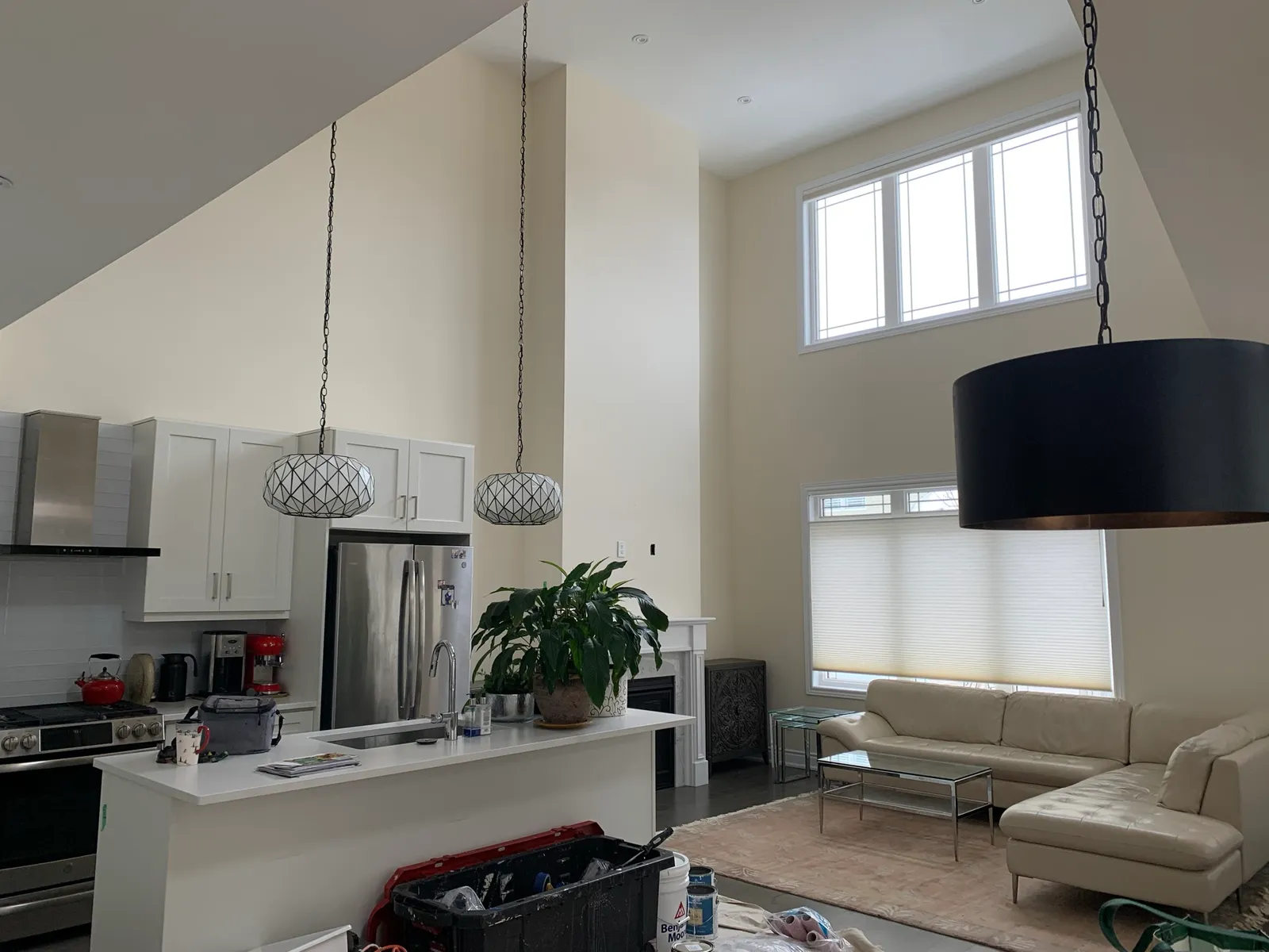 A double height kitchen and great room before painting, the walls plain off-white and the floor still covered.